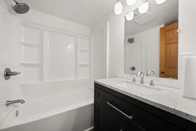 a bathroom with a granite countertop sink a large mirror and a bathtub
