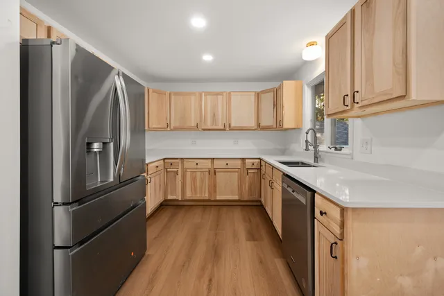 a kitchen with kitchen island a counter top space a sink a refrigerator and cabinets