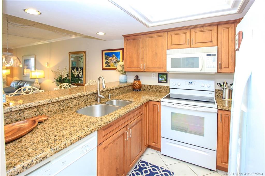 350 Northeast Edgewater Drive, Unit 202 Stuart, FL 34996 - Photo 11 of 28 a kitchen with granite countertop a sink stove and cabinets