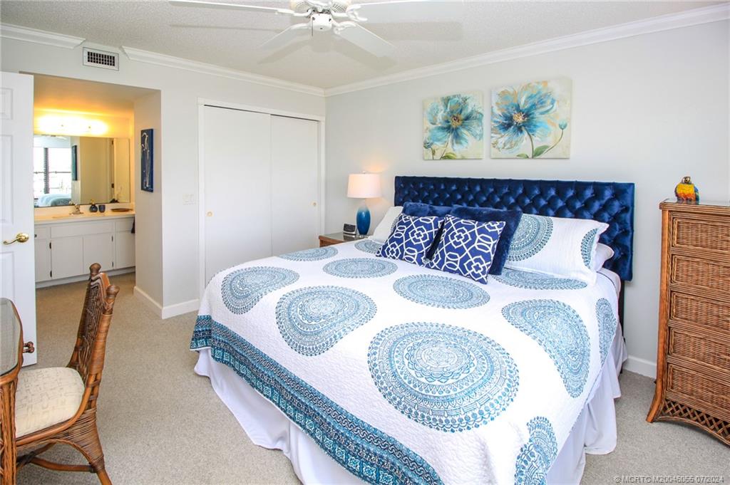 350 Northeast Edgewater Drive, Unit 202 Stuart, FL 34996 - Photo 16 of 28 a bedroom with a bed and a chandelier