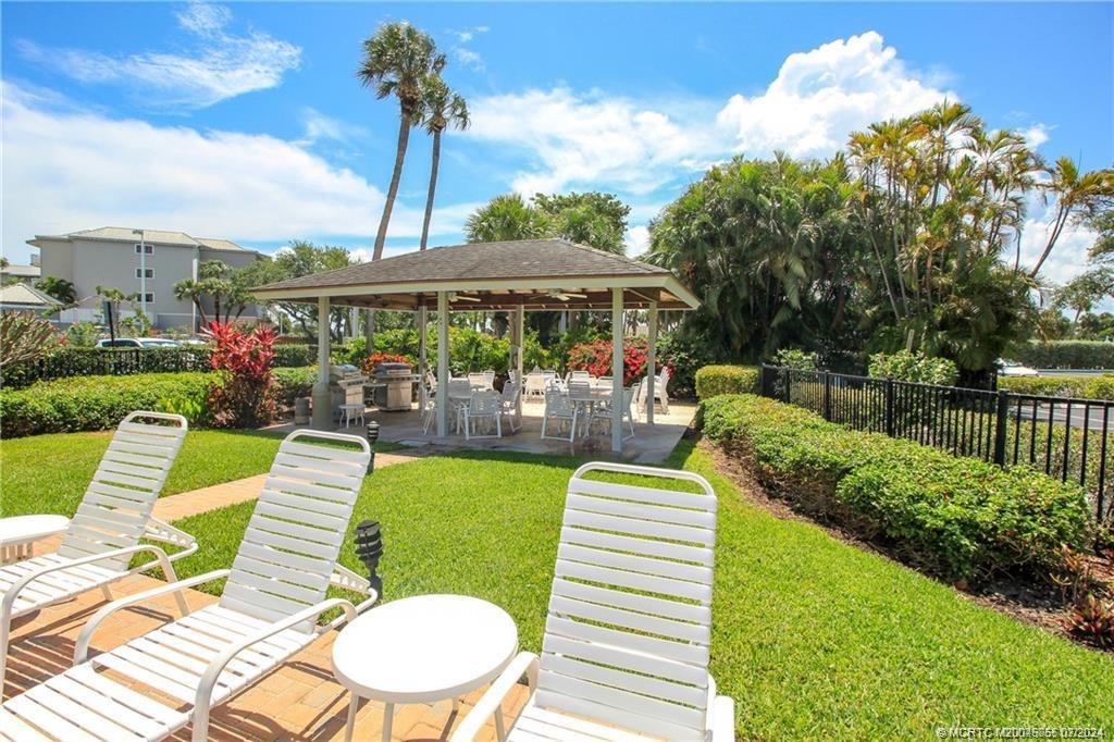 350 Northeast Edgewater Drive, Unit 202 Stuart, FL 34996 - Photo 24 of 28 a view of a chairs and table in patio with a swimming pool