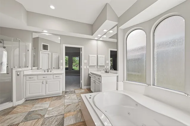 a large spacious bathroom with a granite countertop tub mirror and shower