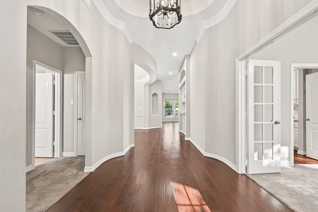 a view of a hallway with wooden floor and a chandelier