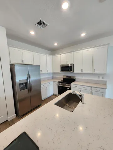 a kitchen with granite countertop a refrigerator sink and cabinets