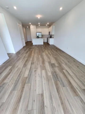 a view of a living room with kitchen and wooden floor