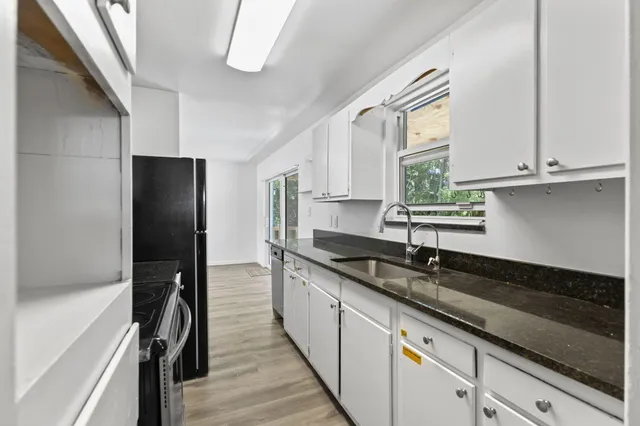 a kitchen with granite countertop stainless steel appliances a sink stove and cabinets