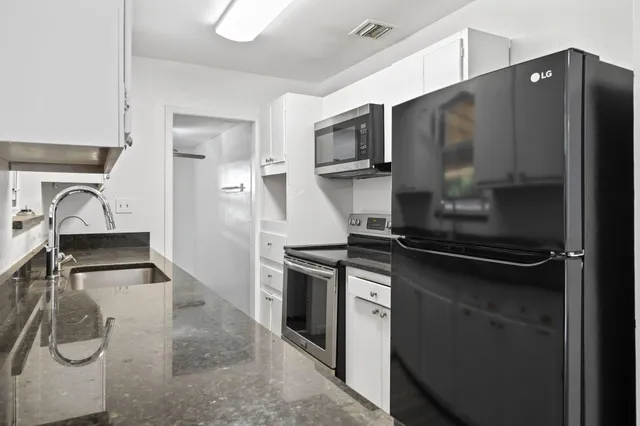 a kitchen with stainless steel appliances granite countertop a refrigerator and a sink