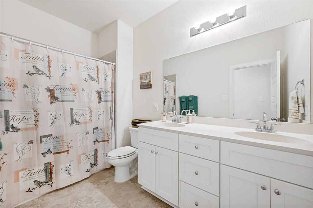 413 Wiggins Way Van Alstyne, TX 75495 - Photo 22 of 25 Bathroom featuring a dual vanity with white cabinetry and integrated sinks, a large wall-mounted mirror, and a toilet