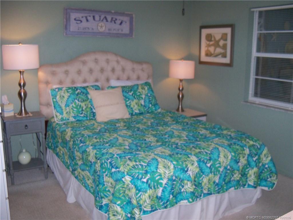 1939 Southwest Palm City Road, Unit G Stuart, FL 34994 - Photo 12 of 34 a bed room with a bed and a lamp