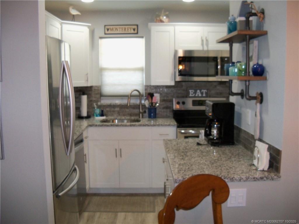 1939 Southwest Palm City Road, Unit G Stuart, FL 34994 - Photo 16 of 34 a kitchen with stainless steel appliances granite countertop a refrigerator and a stove top oven