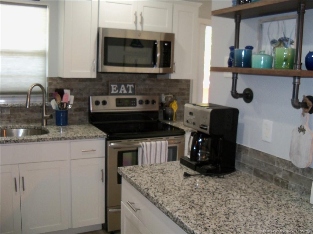 1939 Southwest Palm City Road, Unit G Stuart, FL 34994 - Photo 18 of 34 a kitchen with stainless steel appliances granite countertop a sink stove and microwave