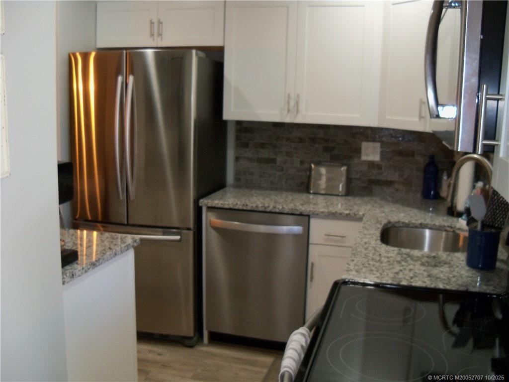 1939 Southwest Palm City Road, Unit G Stuart, FL 34994 - Photo 19 of 34 a kitchen with stainless steel appliances granite countertop a refrigerator a sink and a stove
