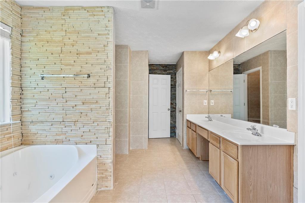 665 Roxford Lane Northeast Buford, GA 30518 - Photo 11 of 19 a bathroom with a tub sink shower and two mirror