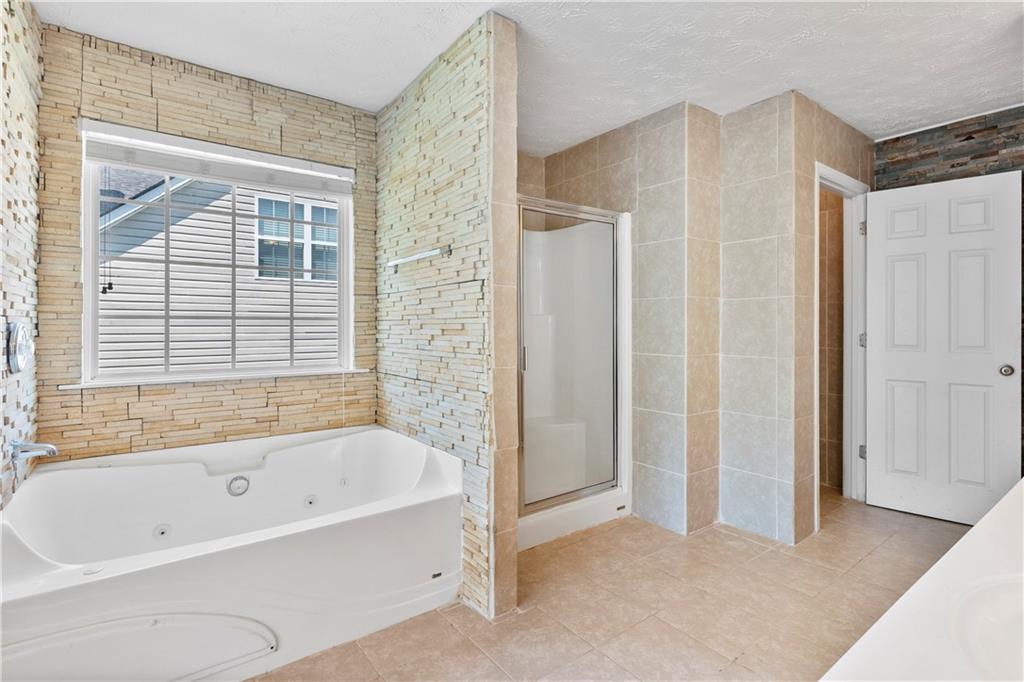 665 Roxford Lane Northeast Buford, GA 30518 - Photo 15 of 19 a bathroom with a bathtub and a shower