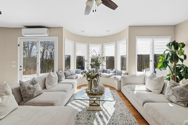 a living room with furniture large windows and wooden floor