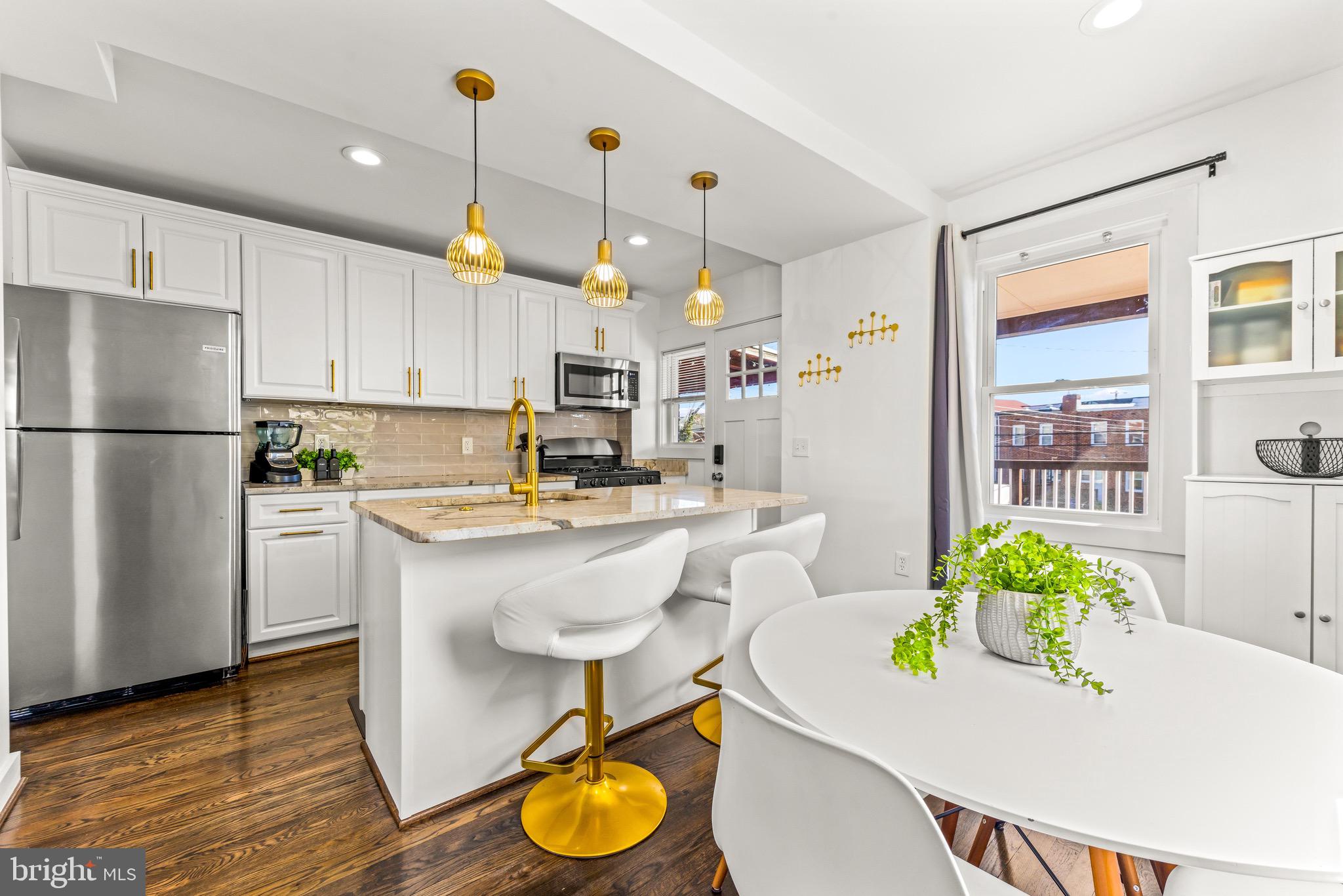 57 Upmanor Road Baltimore, MD 21229 - Photo 5 of 27 a kitchen with stainless steel appliances granite countertop a refrigerator a sink a stove a dining table and chairs with wooden floor