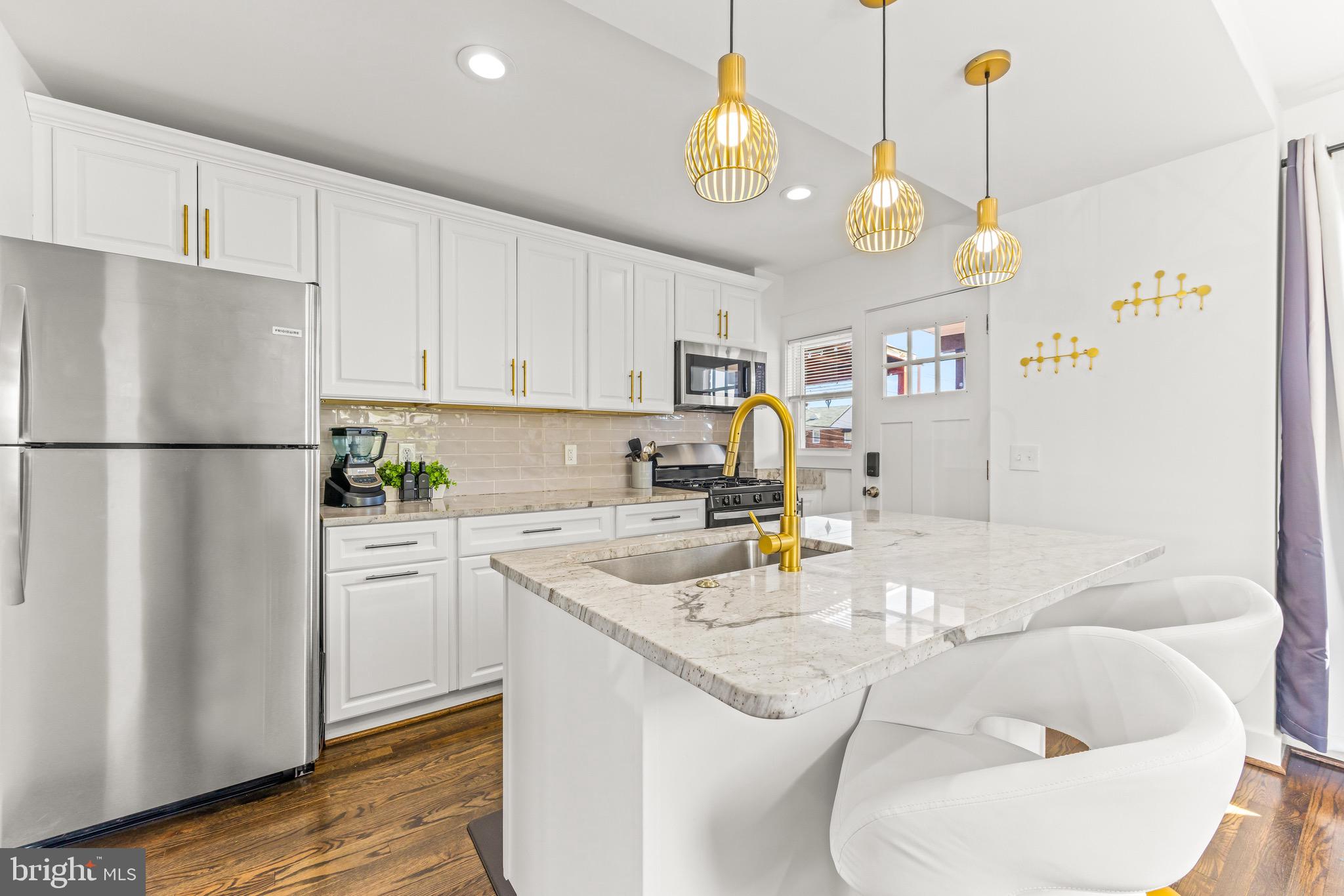 57 Upmanor Road Baltimore, MD 21229 - Photo 6 of 27 a kitchen with stainless steel appliances granite countertop a sink a refrigerator white cabinets and wooden floor