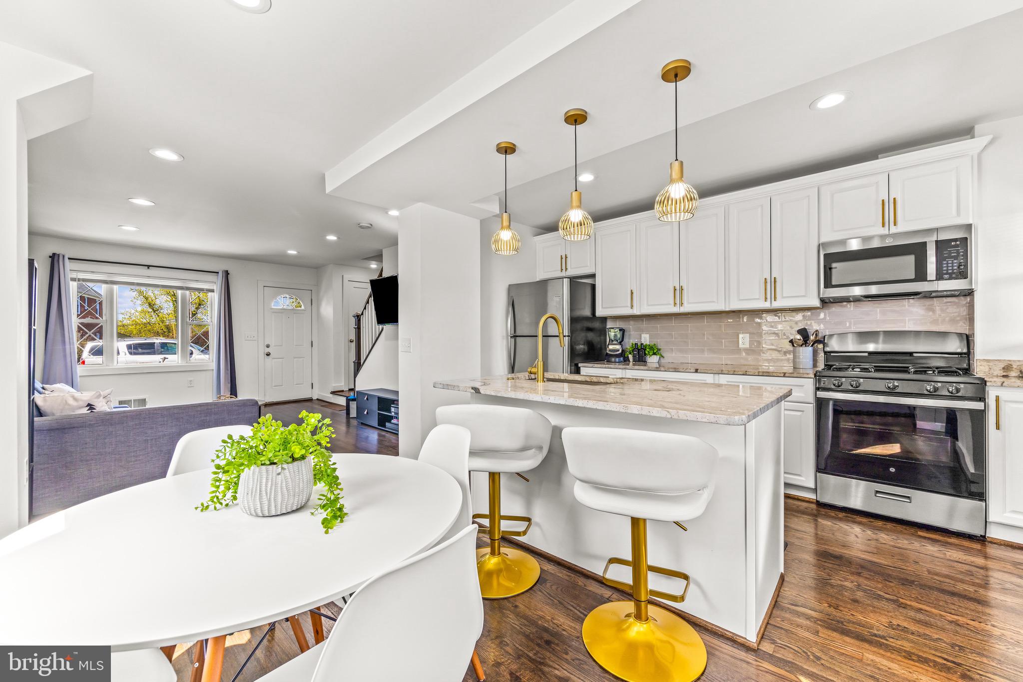 57 Upmanor Road Baltimore, MD 21229 - Photo 9 of 27 a kitchen with stainless steel appliances granite countertop a stove a sink a refrigerator and a dining table with wooden floor