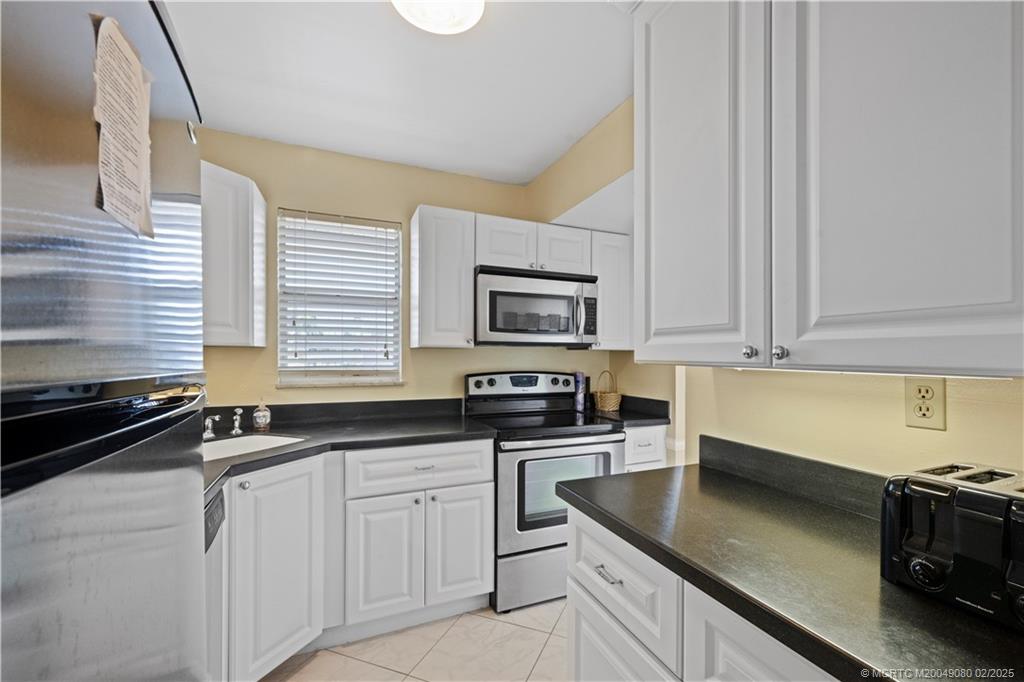 1961 Southwest Palm City Road, Unit F Stuart, FL 34994 - Photo 13 of 29 a kitchen with granite countertop white cabinets and black appliances