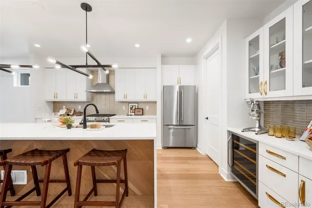 a kitchen with stainless steel appliances granite countertop a sink a stove a refrigerator and island with wooden floor