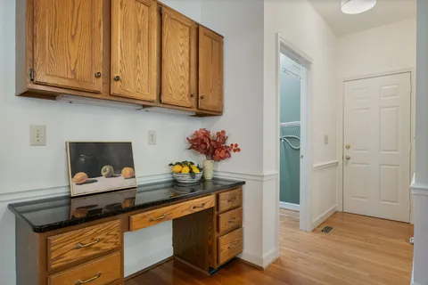 a kitchen with stainless steel appliances granite countertop a coffee maker on granite counter tops and white cabinets with wooden floor