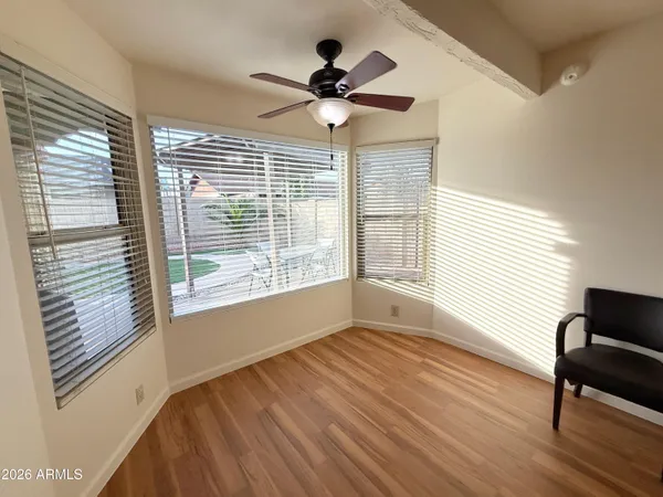 a view of empty room with wooden floor and fan