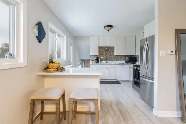 a kitchen with stainless steel appliances a dining table chairs refrigerator and microwave