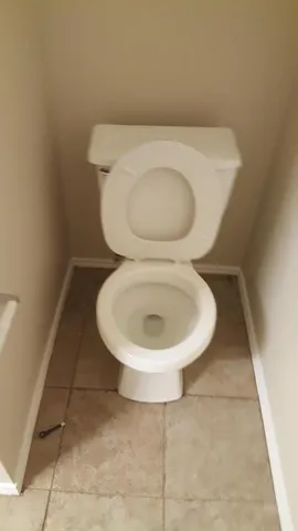 a white toilet sitting next to a white wall
