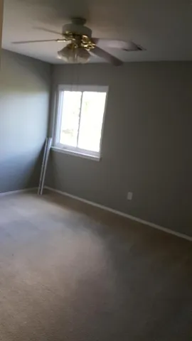 en empty room with windows and ceiling fan