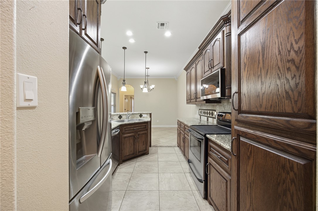 6934 Wooldridge Road, Unit R5 Corpus Christi, TX 78414 - Photo 6 of 32 a kitchen with stainless steel appliances granite countertop a refrigerator and a stove top oven