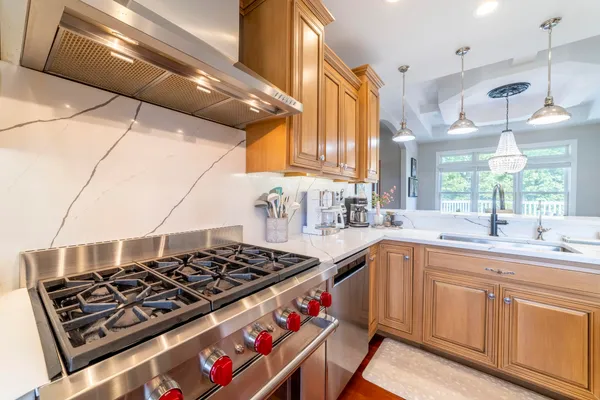 a kitchen with stainless steel appliances granite countertop a stove a sink a dining table and chairs with wooden floor