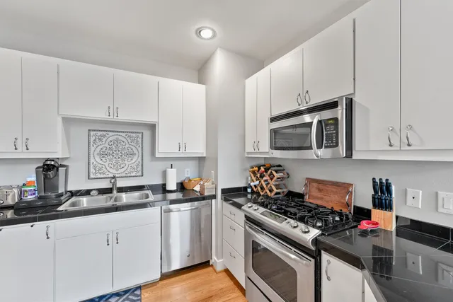 a kitchen with stainless steel appliances granite countertop white cabinets sink and stove