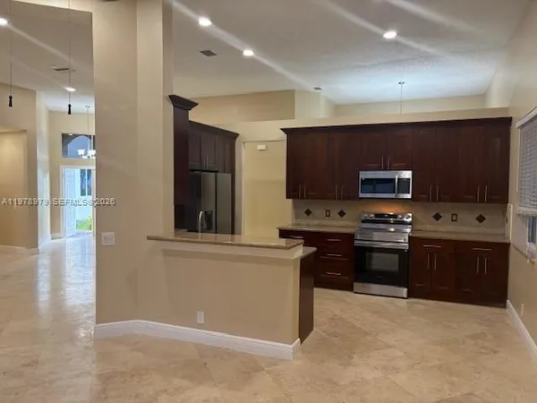 a kitchen with stainless steel appliances kitchen island granite countertop a stove a sink and a microwave