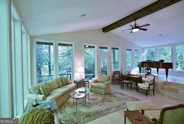 a living room with a fireplace furniture a ceiling fan and a large window