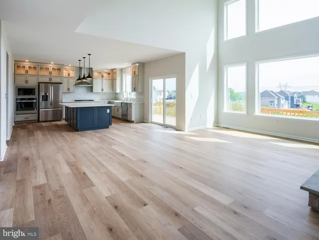 a large kitchen with stainless steel appliances wooden floor and a large window