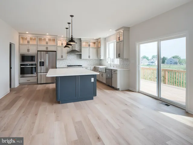 a large kitchen with stainless steel appliances granite countertop a lot of counter space and wooden floors
