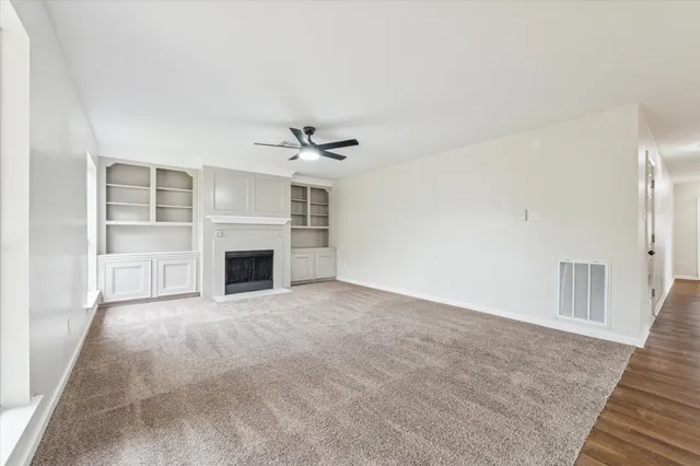 an empty room with windows and fireplace