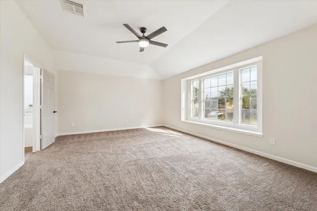 an empty room with windows and fan