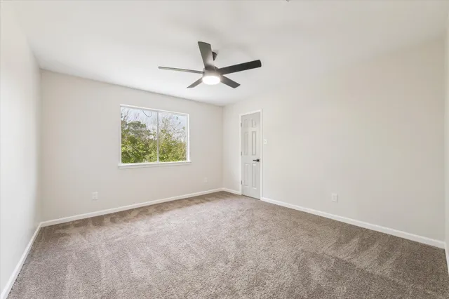 an empty room with window and ceiling fan