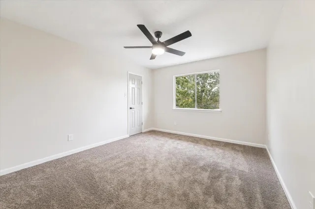 an empty room with window and ceiling fan