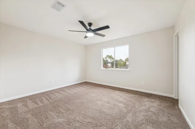 an empty room with windows and fan