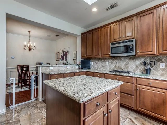 a kitchen with kitchen island granite countertop wooden cabinets dining table and stainless steel appliances