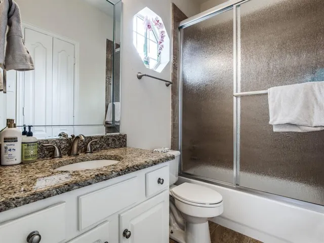 a bathroom with a granite countertop sink toilet and shower