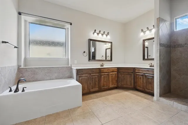 a spacious bathroom with a tub sink and mirror