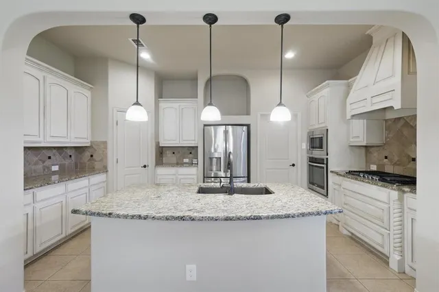 a kitchen with stainless steel appliances granite countertop a sink a stove a refrigerator and a wooden floor