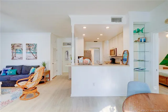 a living room with furniture kitchen view and a chandelier