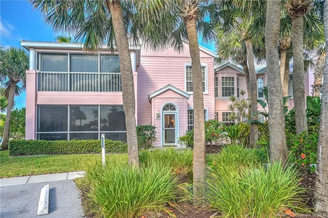 a view of a white house with a yard and potted plants