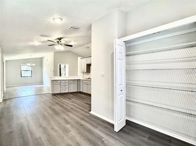 a view of an empty room and chandelier fan