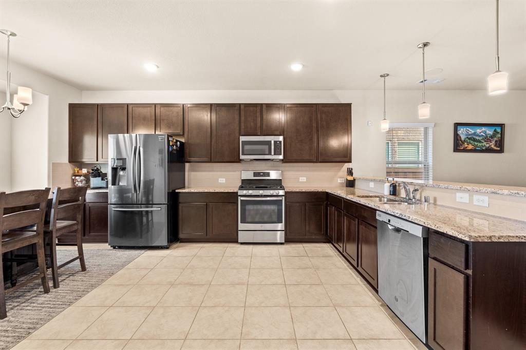 4207 Whispering Willow Way Arlington, TX 76005 - Photo 13 of 31 a large kitchen with stainless steel appliances kitchen island granite countertop a refrigerator and a stove top oven