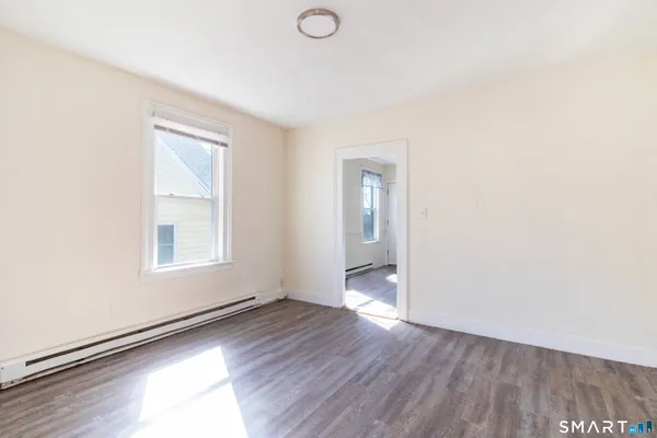 an empty room with wooden floor and windows